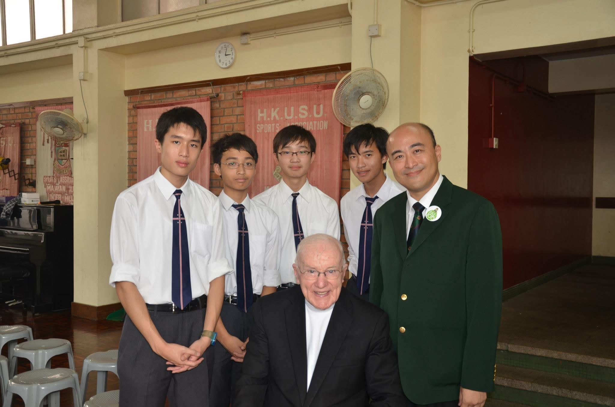 Father Deignan with students and an educator at a school gathering